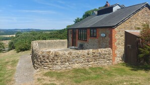 A stone-walled cottage with a small porch and a sign indicating it is a lavender farm. - The Sty (Bridport)