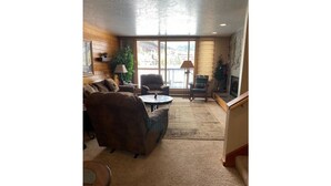 A cozy living room with a large window, a sofa, a coffee table, and a lamp. - Lakeside, Ski Condo with Amazing Views, Quiet, Family-Friendly (Keystone (Dillon))