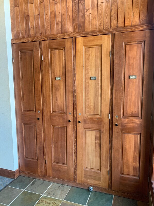 A set of wooden double doors with numbered plaques, indicating room numbers, and a tiled floor.