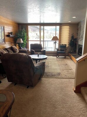 A cozy living room with a large window, a sofa, a coffee table, and a lamp. - Lakeside, Ski Condo with Amazing Views, Quiet, Family-Friendly (Keystone (Dillon))