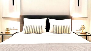 Ett hotellrum med en stor säng, två sängbord med lampor och ett litet dekorativt träd på varje bord.