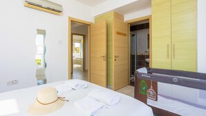 A hotel room with a bed, a wardrobe, a bathroom, and an air conditioning unit. - Villa Marina - Three Bedroom Villa, Sleeps 6 (Pernera)
