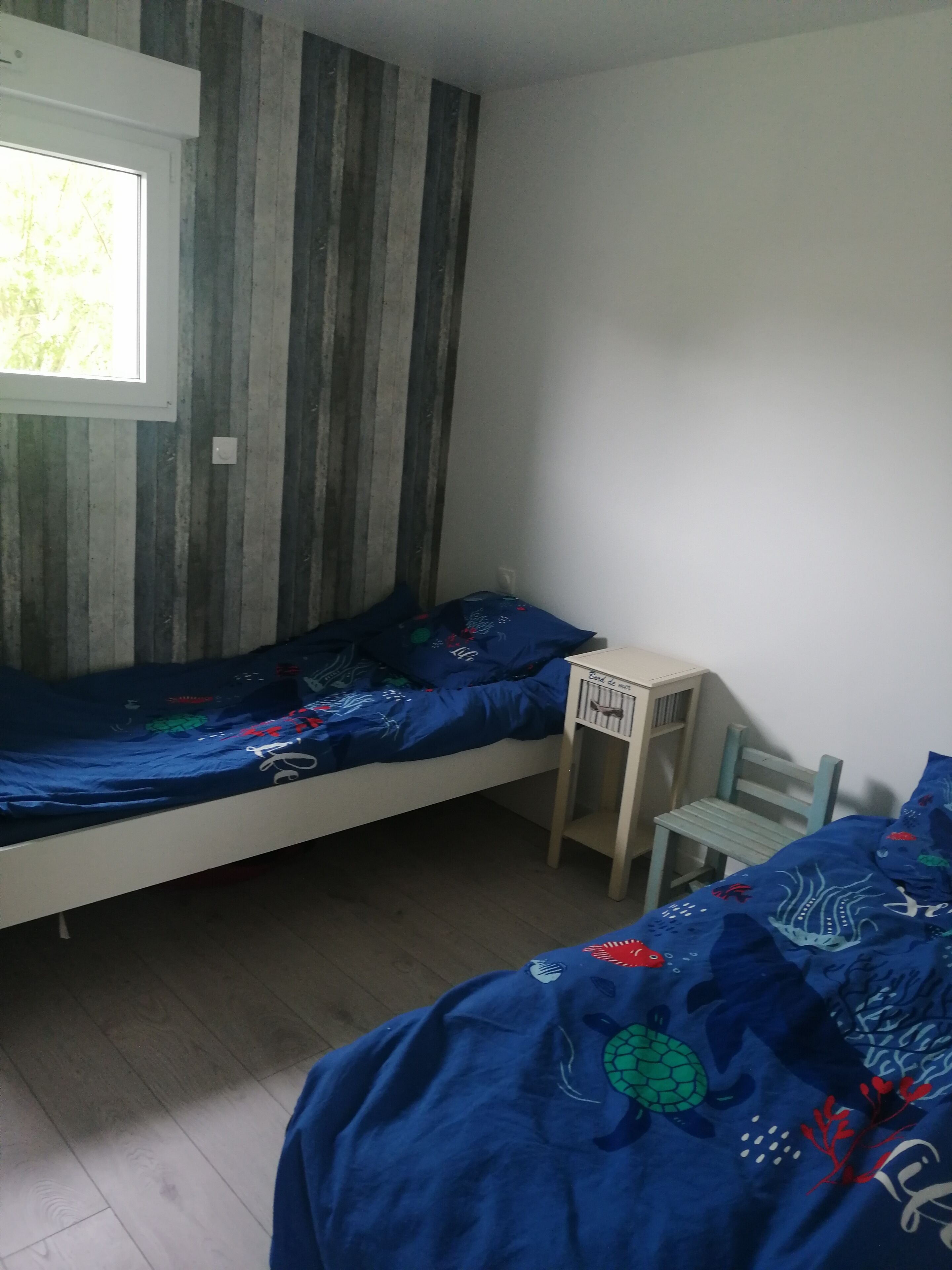 A room with a bed, a small desk, a chair, and a window.