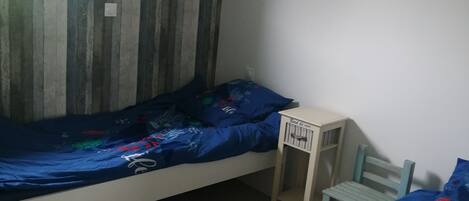 A room with a bed, a small desk, a chair, and a window.