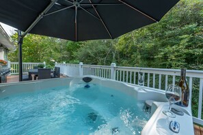 A hot tub with a white deck and a white railing, surrounded by lush greenery. - Hot Tub+Fire Pit, WiFi, Close to AVL+Burnsville! Perfect Location! Easy Access! (Burnsville)