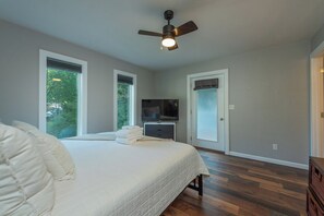 A bedroom with a bed, a ceiling fan, a television, and large windows. - Cozy Cottage~Hot Tub+Fire Pit+Grill~WiFi~Near AVL! (Burnsville)