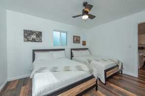 A bedroom with two beds, a ceiling fan, a window, and a door leading to a bathroom. - Cozy Cottage~Hot Tub+Fire Pit+Grill~WiFi~Near AVL! (Burnsville)