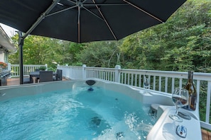 A hot tub with a white deck and a white railing, surrounded by greenery. - Cozy Cottage~Hot Tub+Fire Pit+Grill~WiFi~Near AVL! (Burnsville)