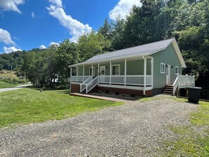 A single-story house with a porch, a front door, and a small staircase leading to the entrance. - Cozy Cottage~Hot Tub+Fire Pit+Grill~WiFi~Near AVL! (Burnsville)