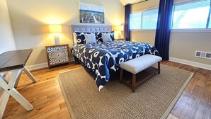 Une chambre à coucher avec un lit, des tables de chevet, un banc, un tapis et un tableau au mur.