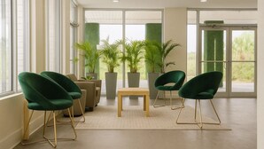 A modern waiting area with green chairs, a wooden table, and potted plants. - Oneway Savannah (Savannah)