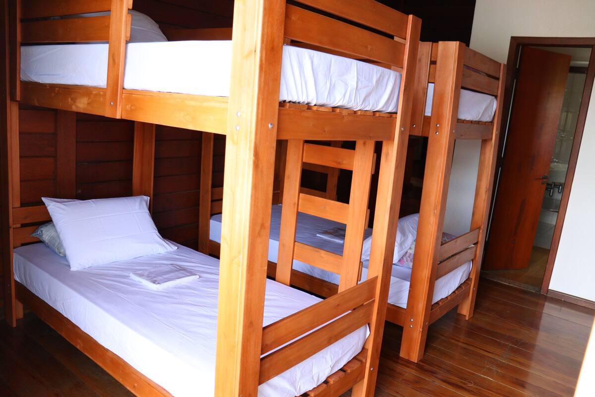 A room with three wooden bunk beds, each with white bedding.