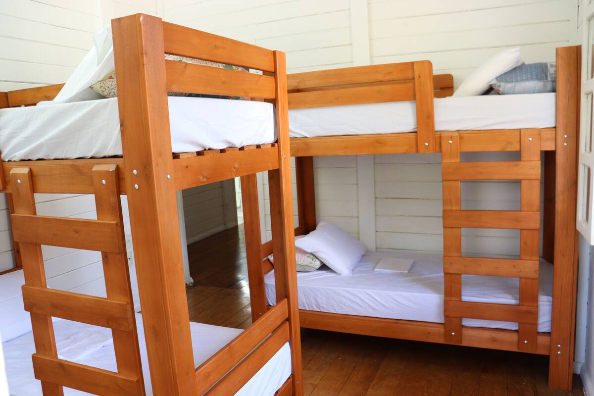 A bunk bed room with wooden frames and white bedding.