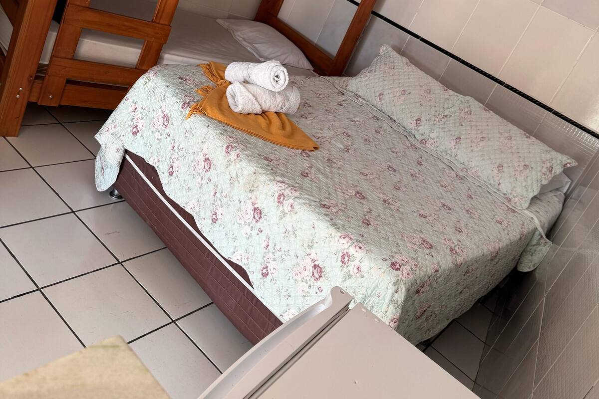 A bunk bed with a floral bedspread and a rolled towel on the lower bunk.