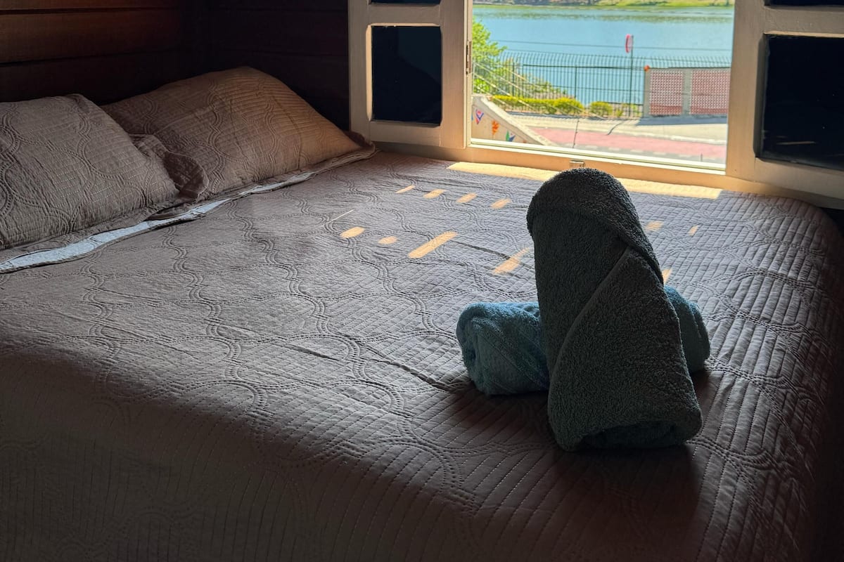 A bedroom with a bed, a window, and a painting on the wall.