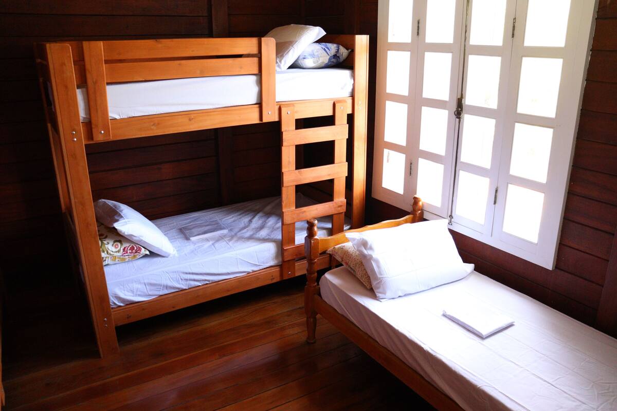A wooden bunk bed room with a window providing natural light.