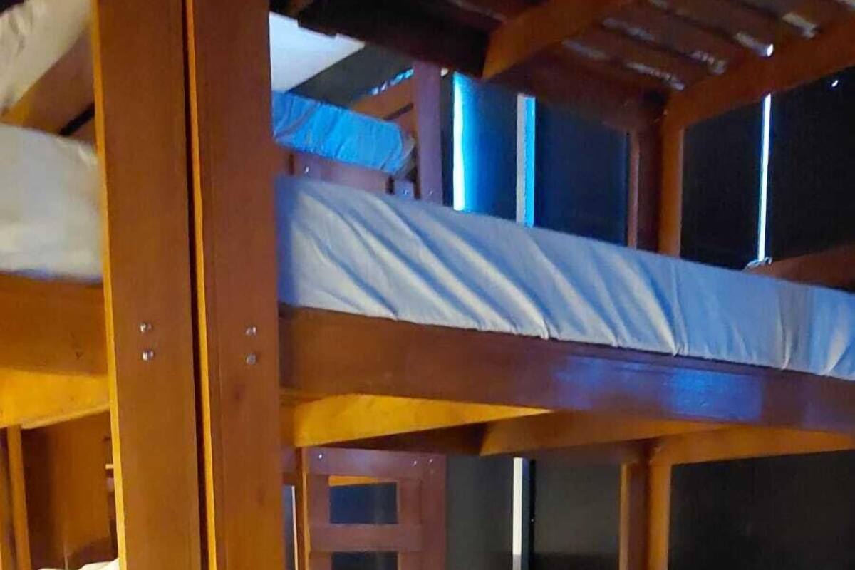 A bunk bed room with wooden frames and white bedding.