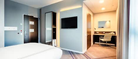 Una habitación de hotel con cama, televisión, escritorio con silla y baño.