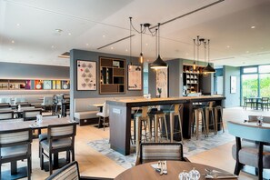 Eine moderne Hotelhalle mit Barbereich, Sitzgelegenheiten und Kunstwerken an den Wänden.