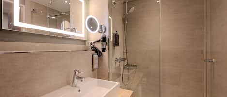 Een moderne badkamer met een grote spiegel, een wastafel, een douche met glazen deur en een handdouche.