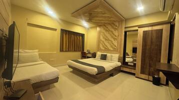 Habitación de hotel con dos camas individuales, una cama grande, cabecero de madera, un espejo, un armario y un televisor.