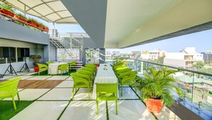 A rooftop terrace with green chairs, a table, and potted plants. - The Tripti Hotel (Indore)