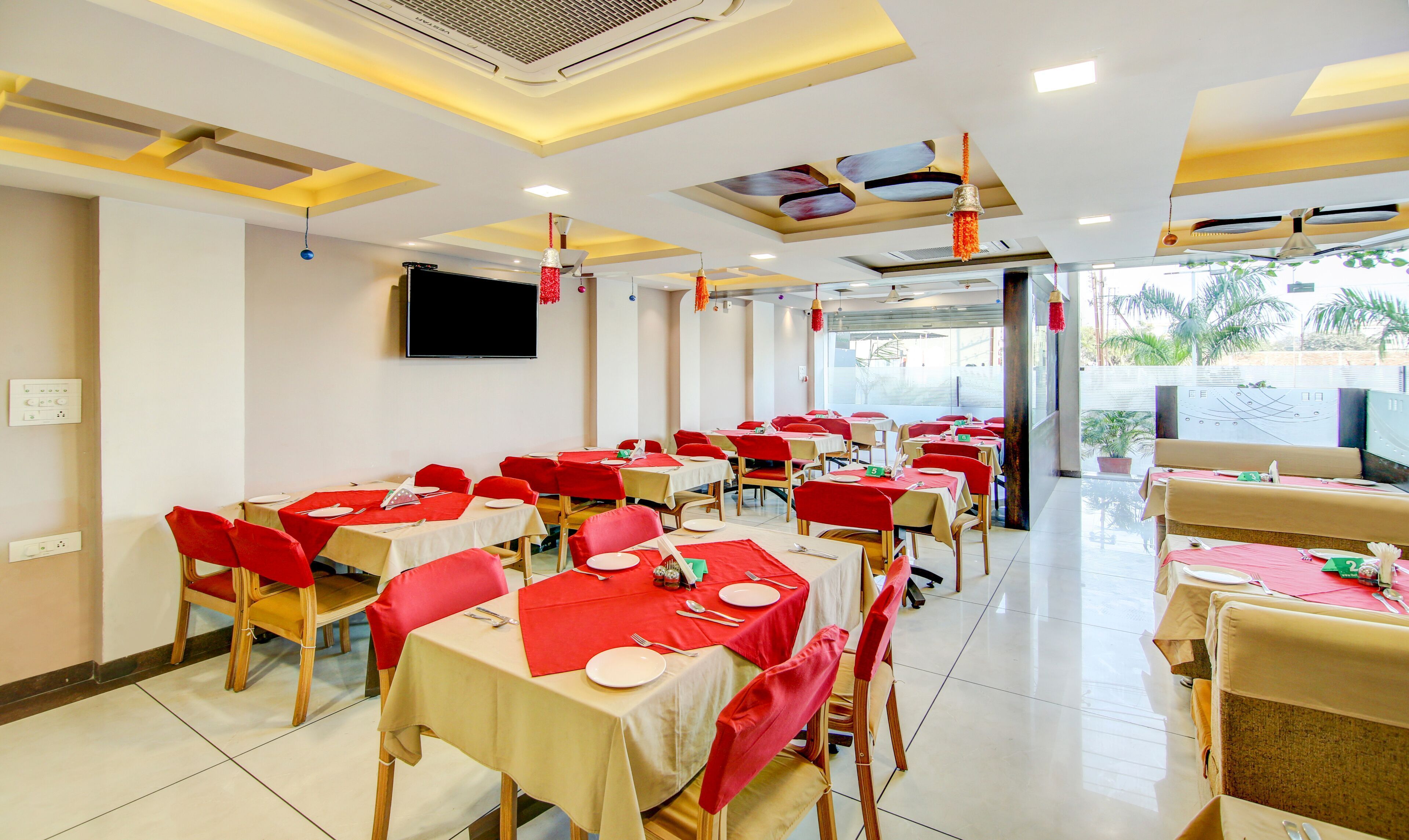 Un restaurant avec de nombreuses tables, chacune recouverte d’une nappe rouge et agrémentée d’assiettes blanches.