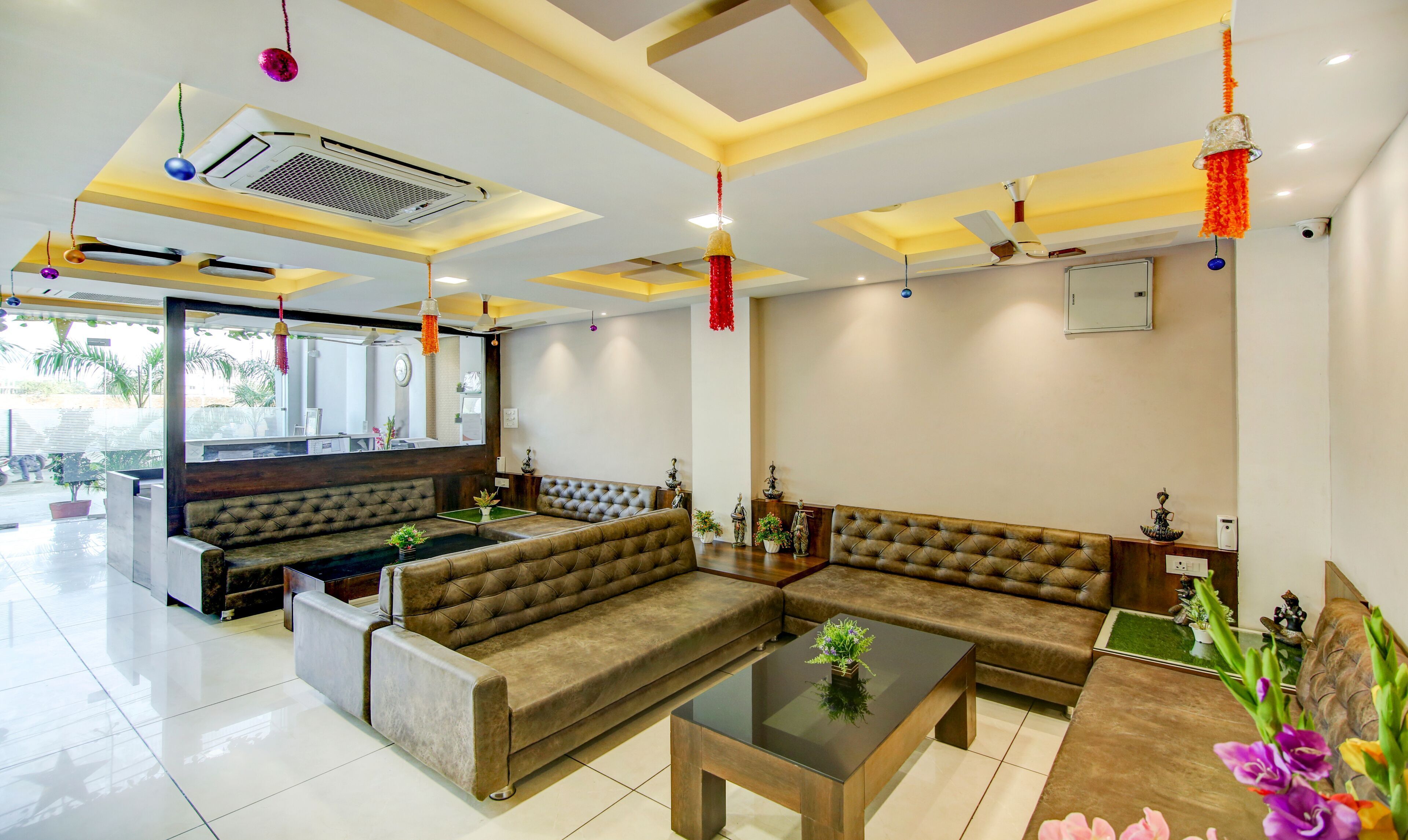 A modern hotel lobby with a seating area, a reception desk, and a large window providing a view of the outside.
