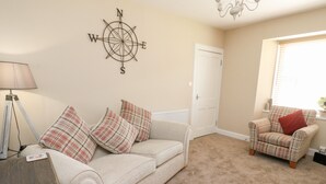 A living room with a beige sofa, a plaid-patterned armchair, and a compass wall decoration. - Ulla Dhu (Nethy Bridge)