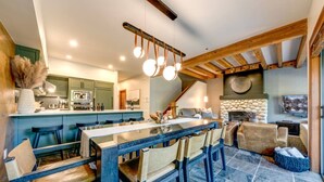 Un vaste espace de vie comprenant une grande table à manger en bois, des sièges confortables et une cheminée en pierre.