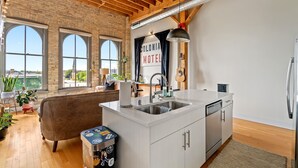 Una cocina con encimera blanca, pileta de acero inoxidable y un cartel que dice "Colonia Motel".