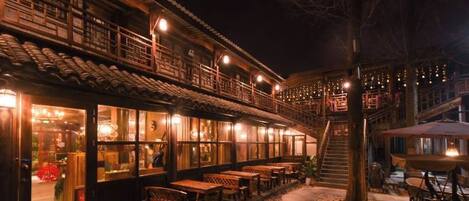A traditional building with a covered outdoor seating area and a staircase leading to an upper level.