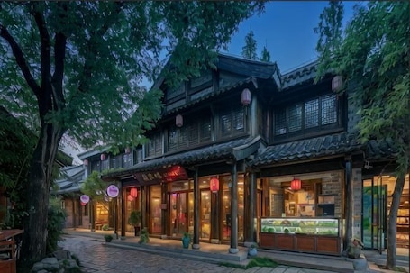 A traditional building with a tiled roof, wooden facade, and a storefront with glass display cases.. Huajiadi Inn (Taierzhuang Ancient City Scenic Area)
