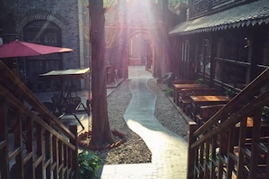 A courtyard with wooden benches, a central pathway, and a building with a tiled roof. - Huajiadi Inn (Taierzhuang Ancient City Scenic Area) (Zaozhuang)