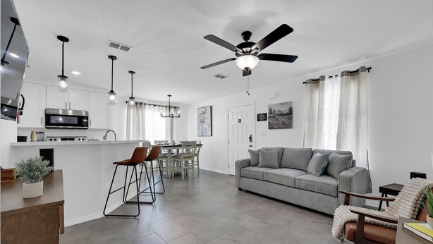 Eine moderne Küche mit Kochinsel, Essbereich mit Stühlen, einer Sitzecke und einem Deckenventilator.