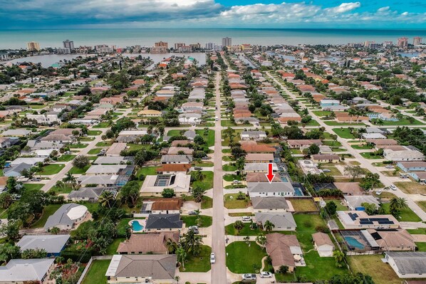 An aerial view of a residential area with houses, roads, and a body of water in the background.