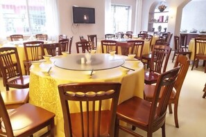 A dining area with round tables, chairs, and a television mounted on the wall. - Jinjiang Inn Select Hotel (Jinggangshan Scenic Area Bus Station) (Jinggangshan City)