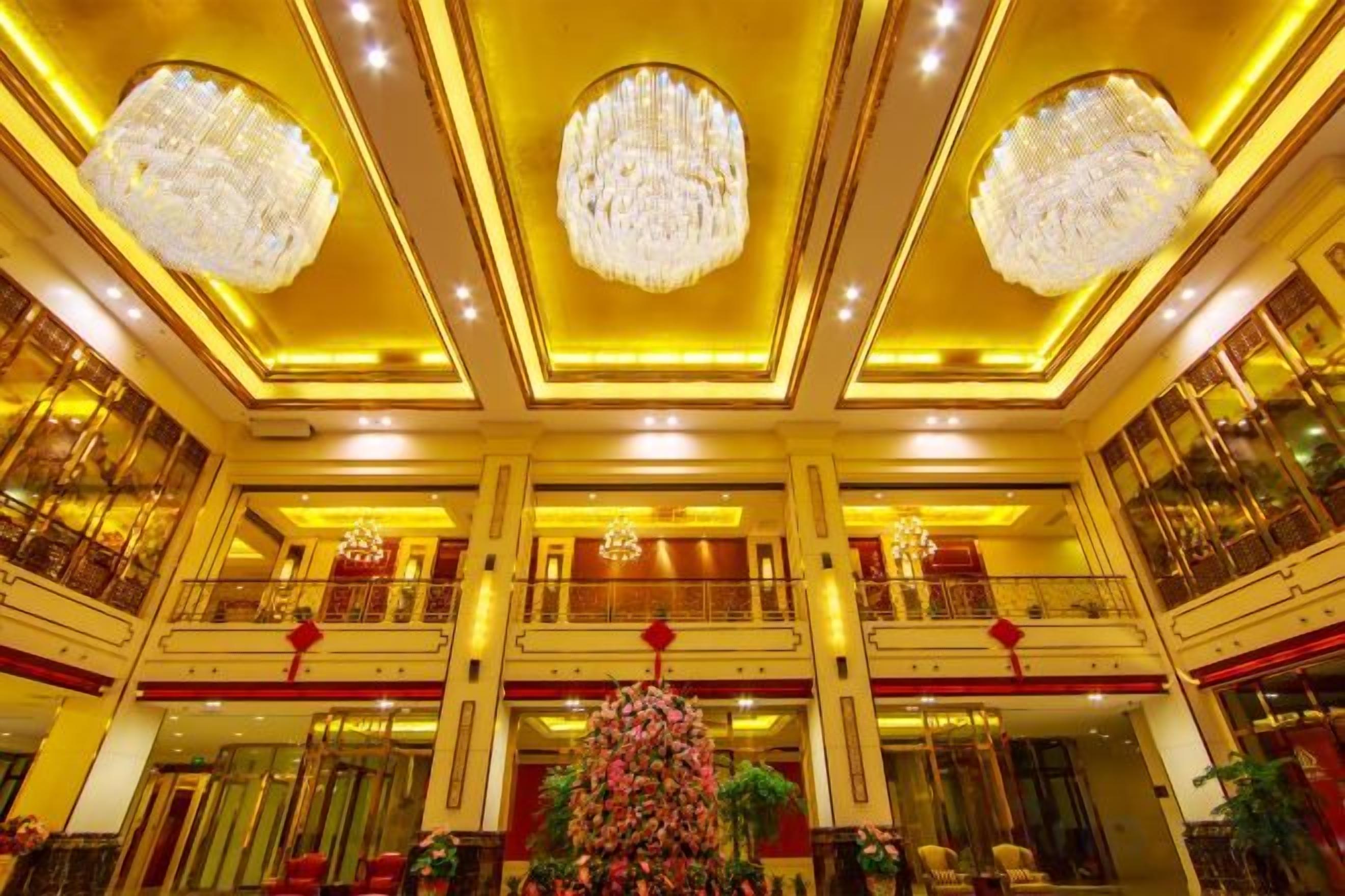 A grand lobby with chandeliers, a Christmas tree, and multiple balconies.