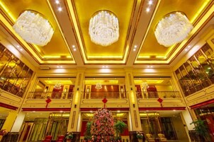 Un lobby espacioso con candelabros, un árbol de Navidad y varios balcones.
