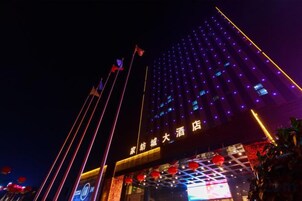 Un hotel con fachada moderna, ventanas iluminadas y una entrada destacada con señalización.