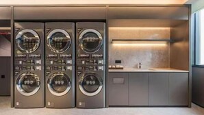 Un moderno cuarto de lavandería con cuatro lavadoras apiladas y una encimera con un lavabo.