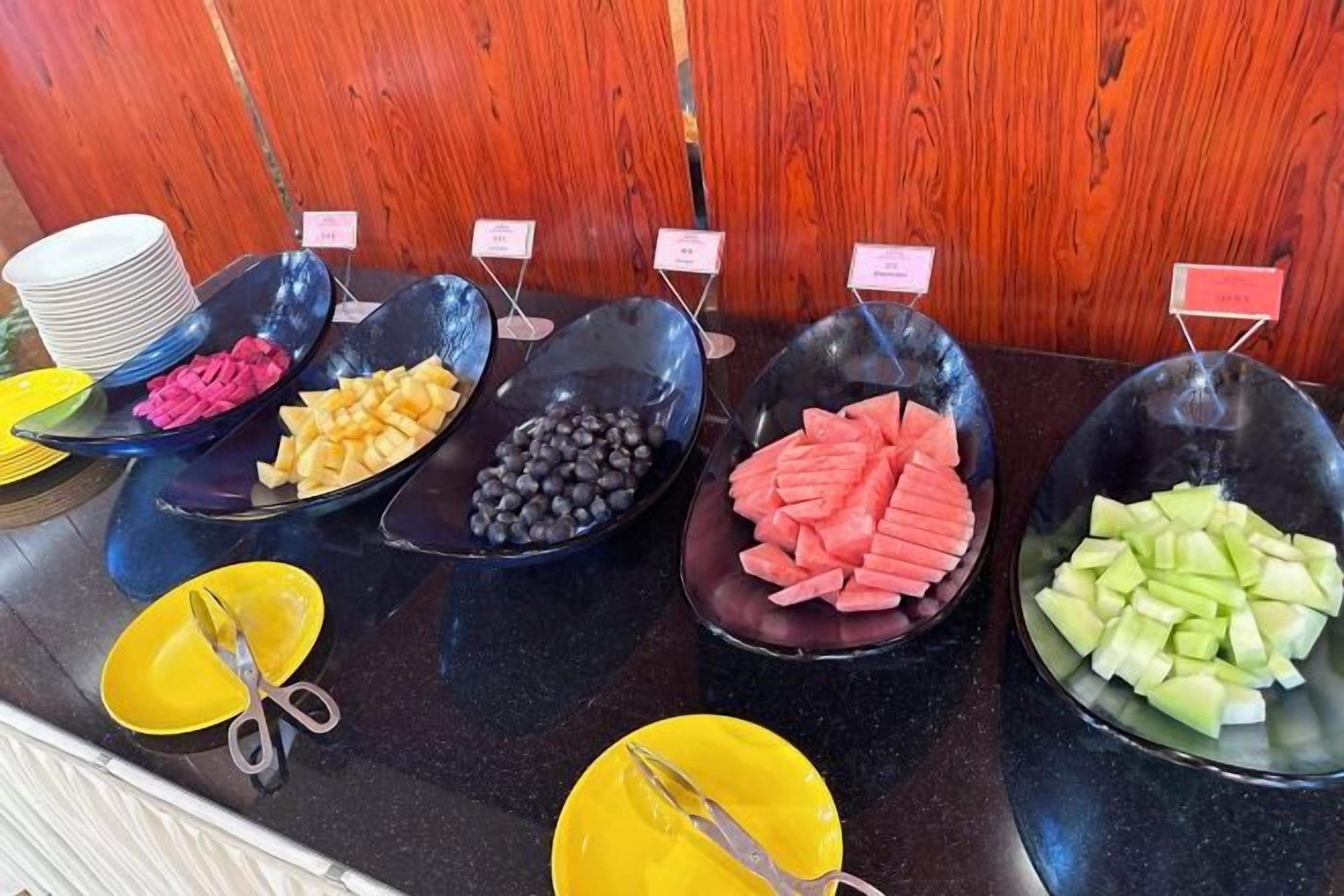 A buffet with various food items in black bowls, each labeled with a small sign.