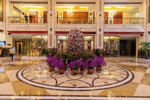 A hotel lobby with a central floral arrangement, a grand staircase, and a chandelier. - Textile City Hotel (Nantong)