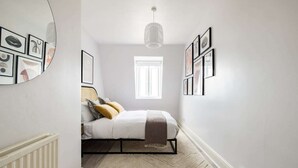 Ein Schlafzimmer mit Bett, Fenster und Wandbildern.