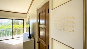 A room with a large window, a wooden door, and a wall with a motivational quote.