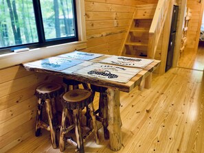 Un intérieur rustique en bois, avec une table sur laquelle sont disposés quatre panneaux, une fenêtre et un plancher en bois.