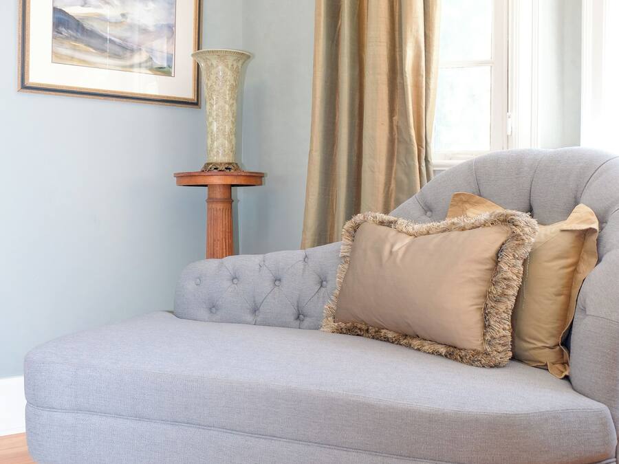 A light grey sofa with a tufted design, positioned on a patterned rug.