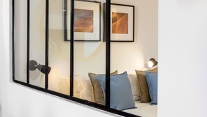 Une chambre moderne avec un lit, une table de chevet et une lampe. Des tableaux encadrés ornent le mur.