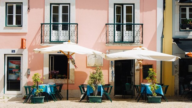 Un café en plein air avec des tables, des chaises, des parasols et des plantes en pot.