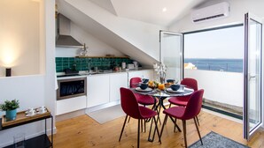 A modern kitchen with a dining area, a view of the sea, and a staircase leading to an upper level. - Turquoise River View II by LovelyStay (Lisboa)